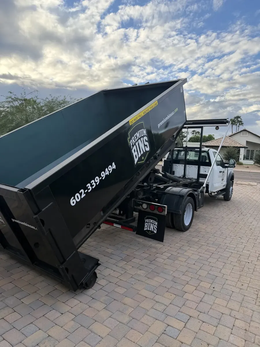 Premium Bins truck setting a 15-yard dumpster down on a paver driveway